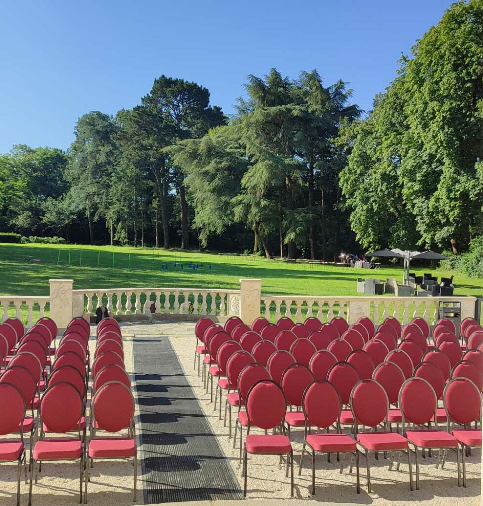Configuration en plein air pour séminaire au Château Le Saz avec chaises rouges face au parc
